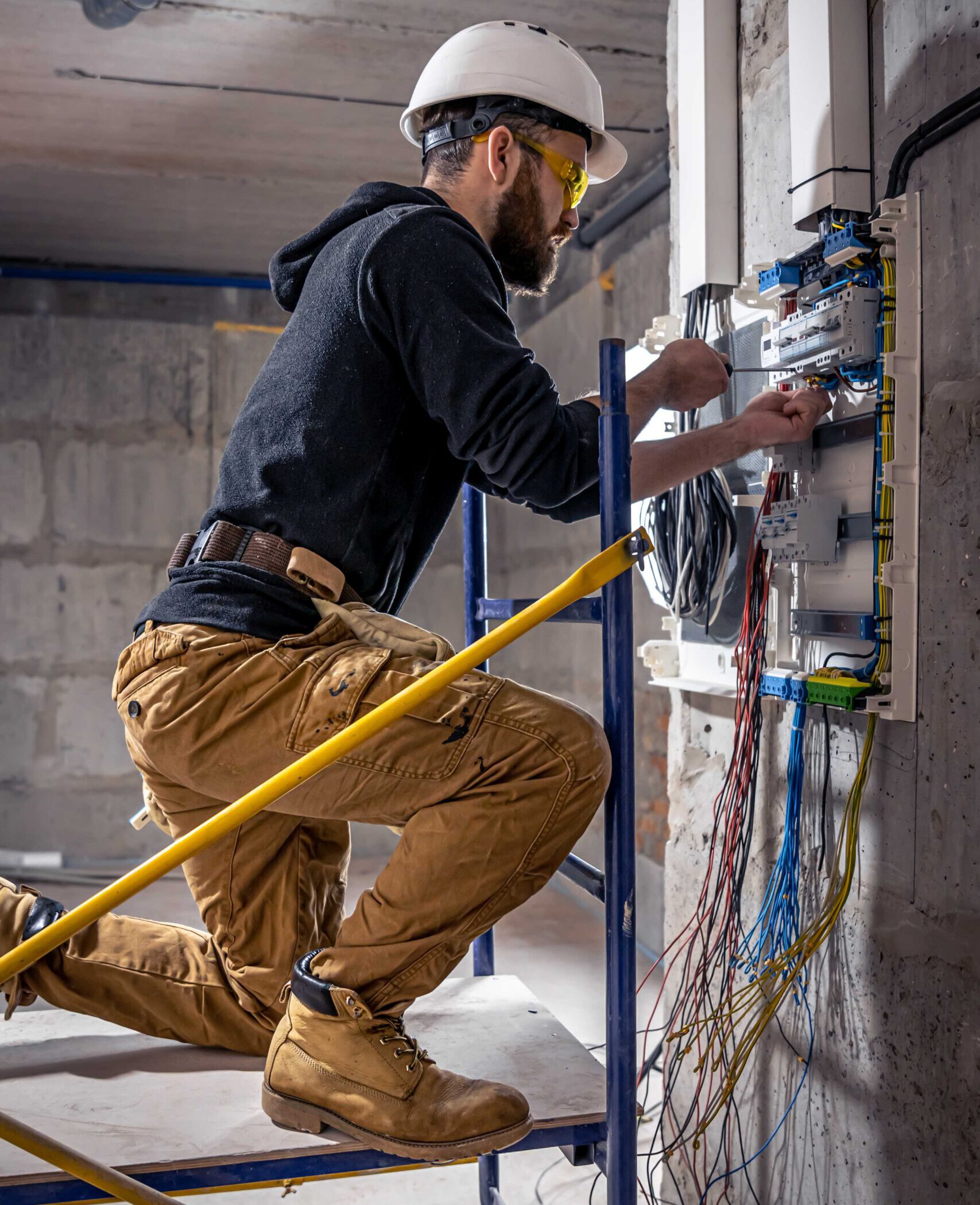 A male electrician works in a switchboard with an electrical connecting cable. Waku Sanitär und Heiztechnik Bad sanierung