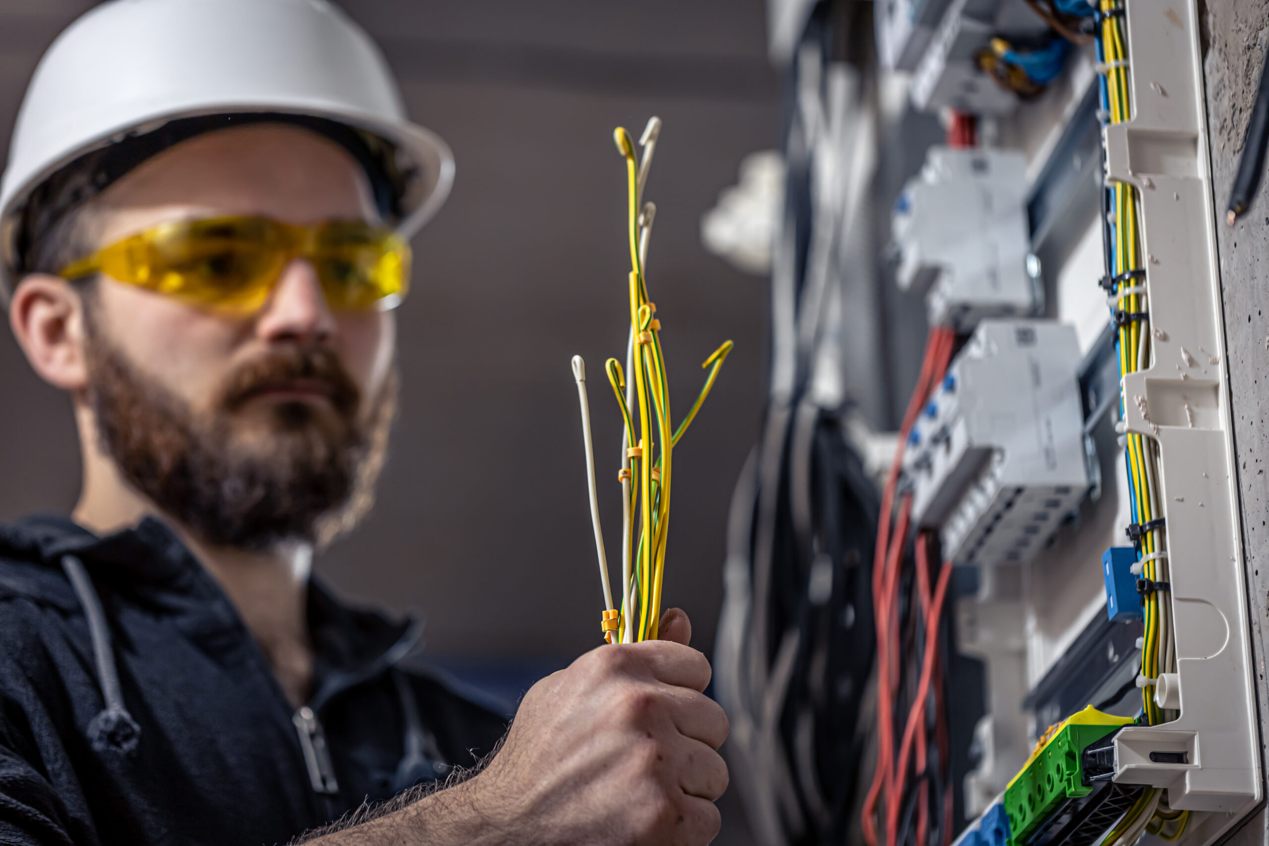 A male electrician works in a switchboard with an electrical connecting cable. Waku-Sanitaer-und-Heiztechnik-heating-system-installation